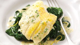 Smoked Haddock with Chive Butter Sauce on a bed of spinach in a white bowl