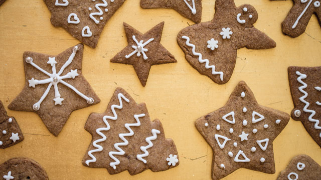 Spiced Christmas Tree Cookies in different shapes on a wooden table decorated with icing
