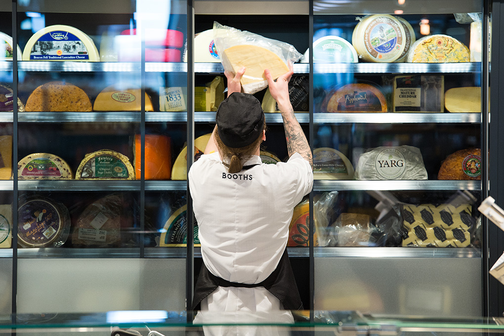 Image of a colleague at Booths St Annes placing a large block of cheese in the fridge