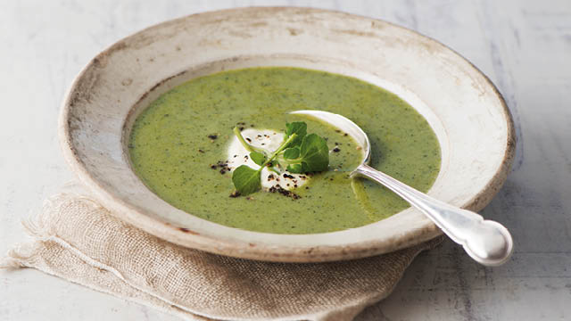 Chilled Yorkshire Pea, Watercress and Mint Soup served in a rustic grey bowl topped with crème fraiche and black pepper