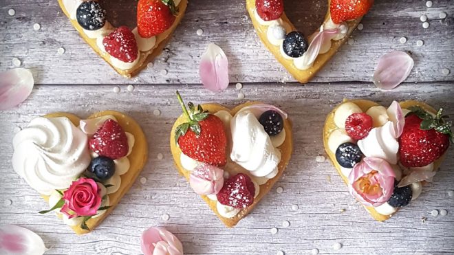 Strawberry Shortbread served in heart shapes and topped with fruit, meringue, cream and dusted with icing sugar