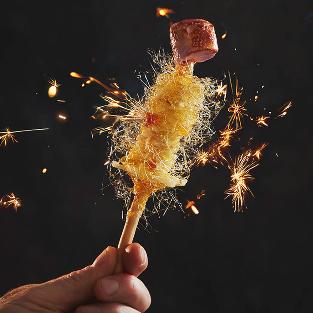 A close up image of someone holding a toffee apple sparkler