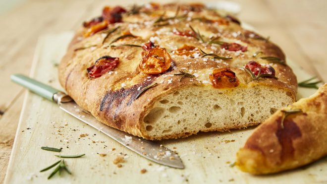 Tomato, Rosemay and Sea Salt Focaccia sliced and served on a wooden board