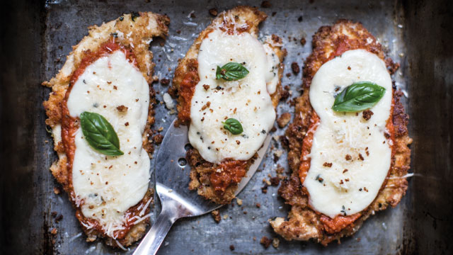 Three servings of turkey parmigiana topped with basil leaves