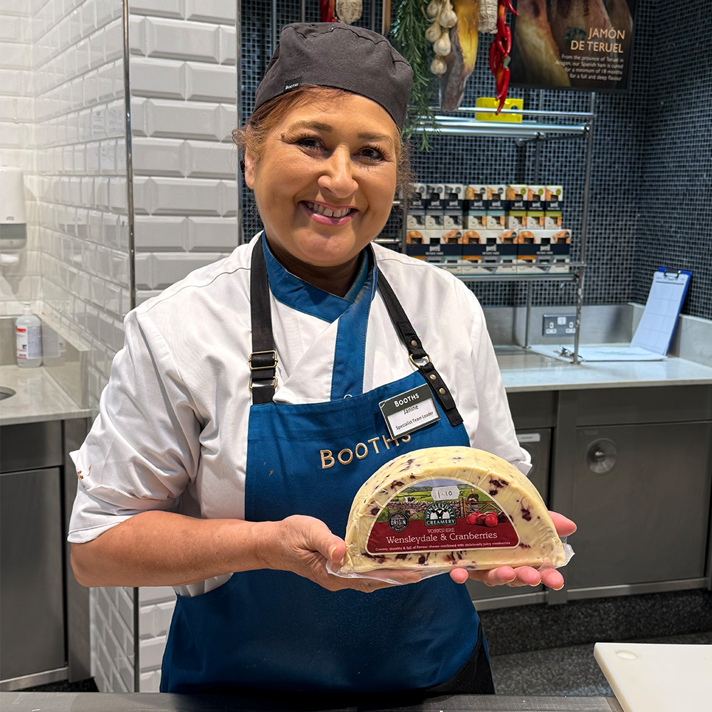 Image of a Booths colleague holding some Wensleydale and Cranberry cheese