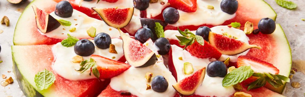 Watermelon Pizza sliced and topped with figs, strawberries and blueberries