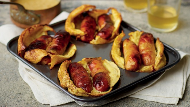 Toad-In-The Hole with a Twist served in a yorkshire pudding baking tray, on top of a white tablecloth