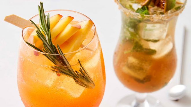 Aperol and Prosecco Peach Fizz served in a glass with ice and a sprig of rosemary