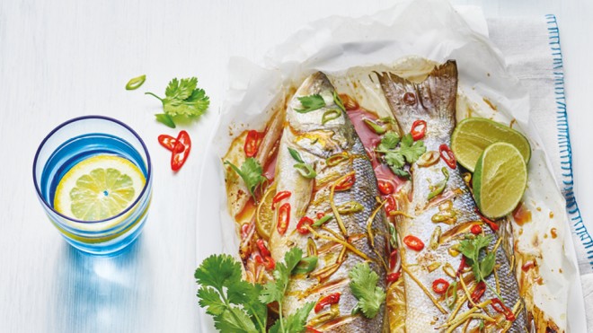 Asian Style Grilled Fish served on baking paper topped with coriander and lime wedges