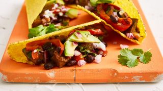 Aubergine Tacos served on a wooden board with avocado and red onion