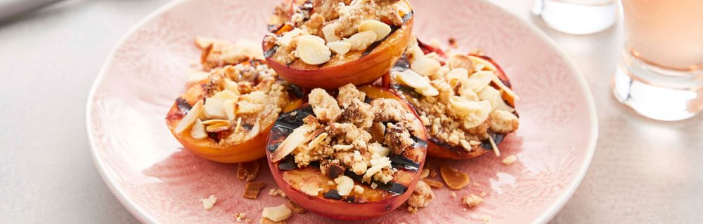 BBQ Grilled Peaches with Amaretti Crumble served on a pink plate