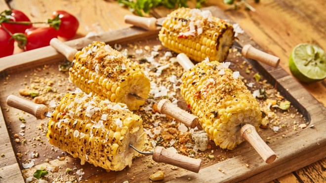 BBQ Sweetcorn with Chilli Butter, served on corn holders, on a wooden board