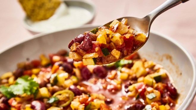 Mixed Bean Chilli served in a white dish with a sppon lifting some of the chilli out