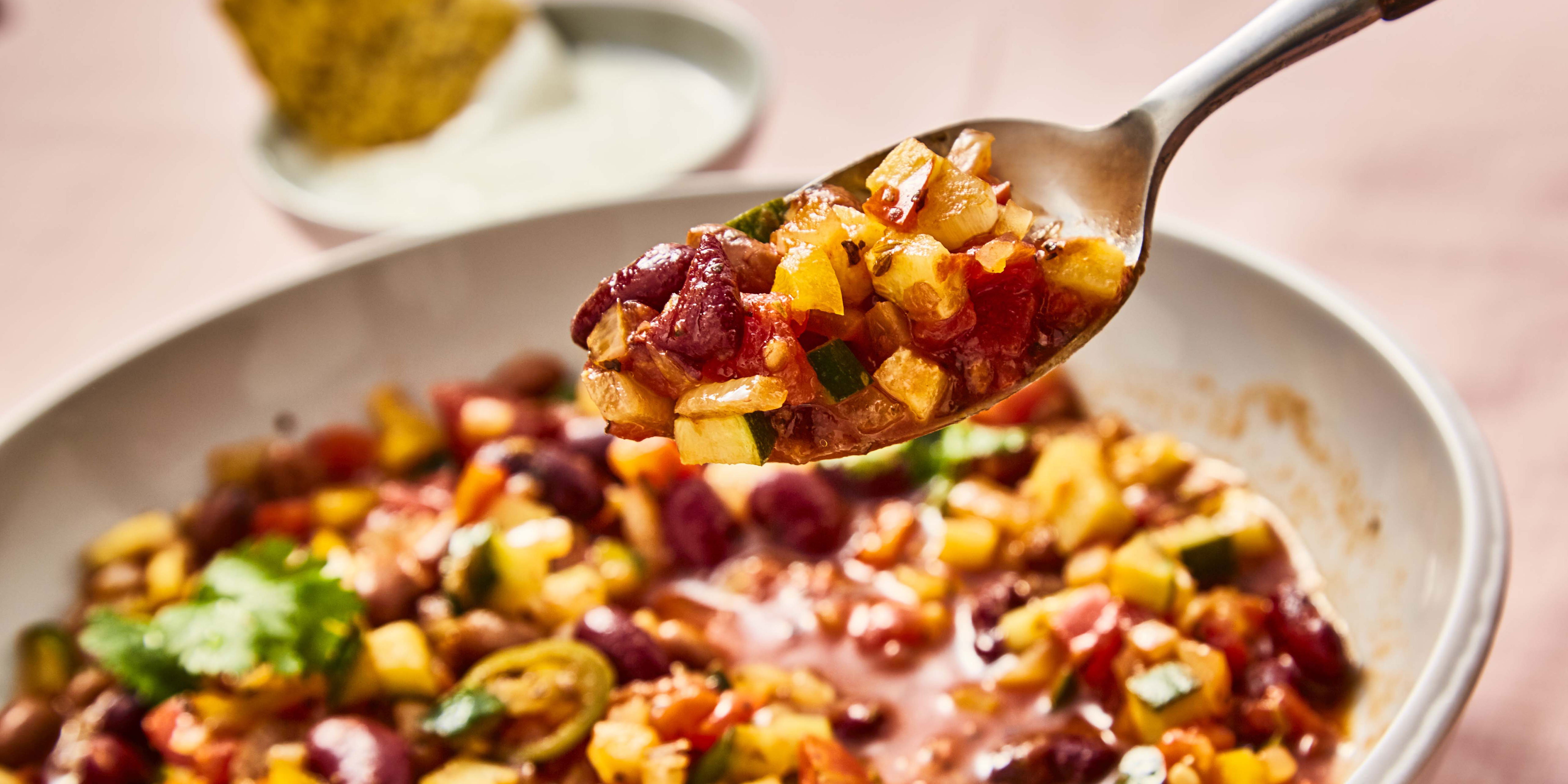 Mixed Bean Chilli served in a white dish with a sppon lifting some of the chilli out