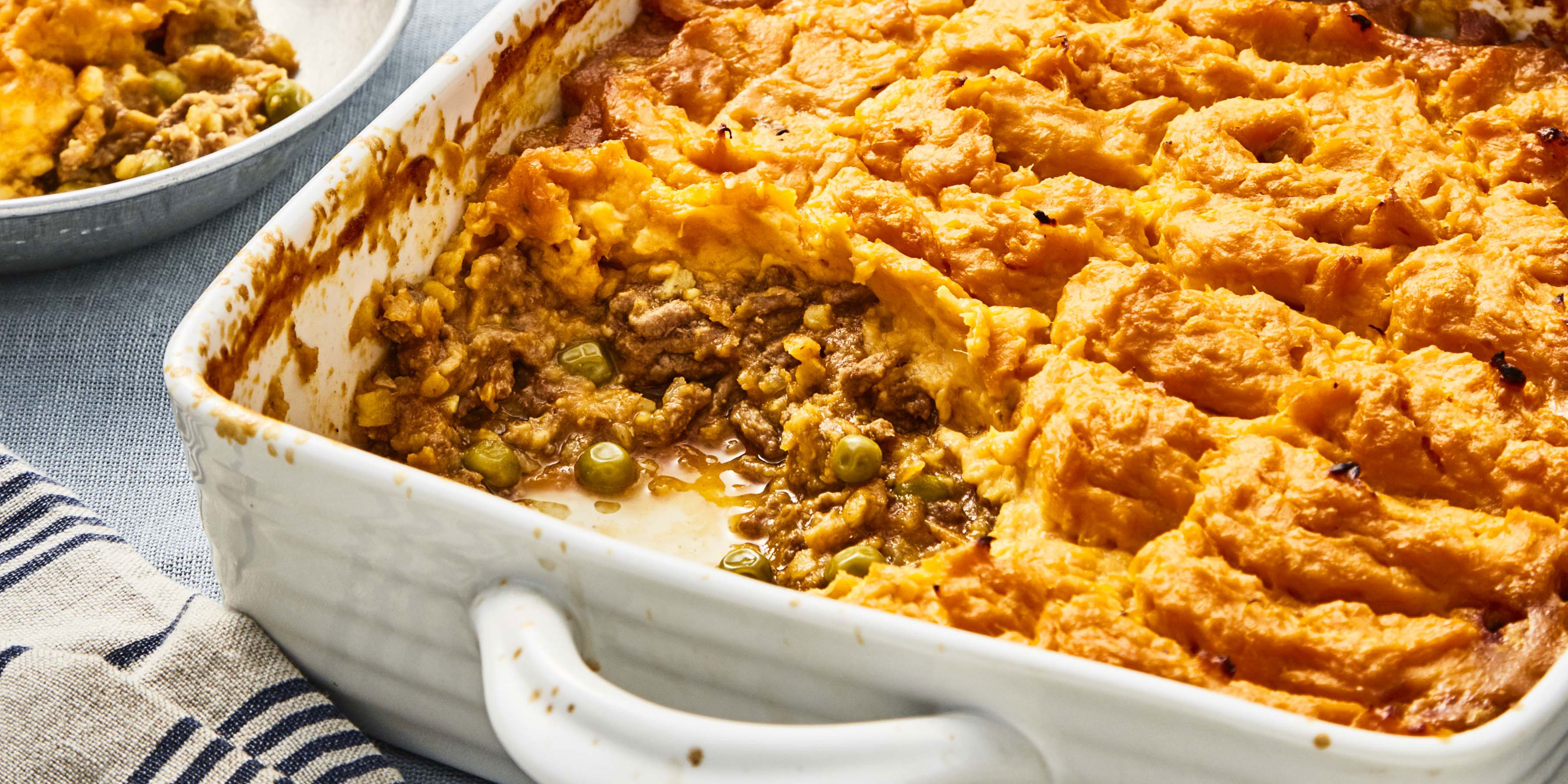 Spiced Beef and Lentil Bake with Sweet Potato Topping served in a white casserole dish with a portion removed to see the filling