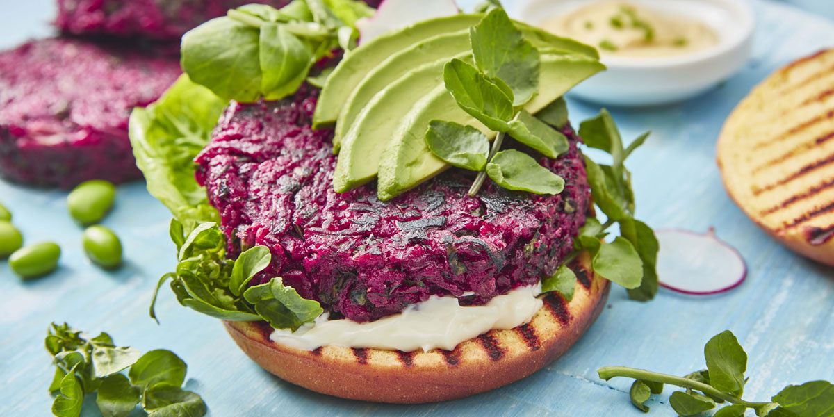 Beetroot Burger served on a toasted brioche bun, with mayonnaise, sliced avocado and watercress