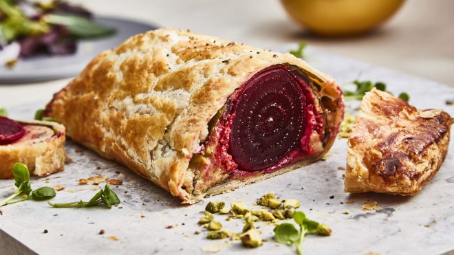 Beetroot Wellington served on a marble board, sliced to see the filling