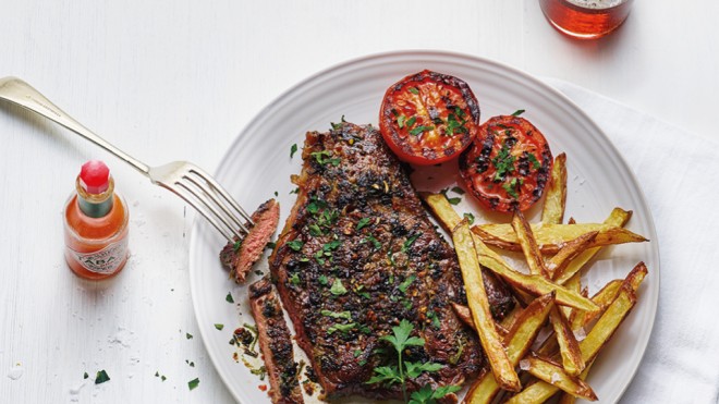 Bloody Mary Rump Steak served on a white plate with homemade chips, grilled tomatoes and topped with parsley