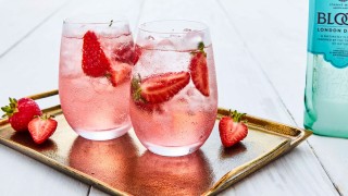 Gin in Full Bloom served in two glasses with ice and sliced strawberries