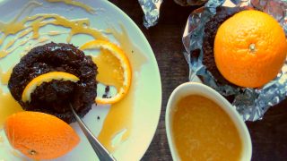 Chocolate Brownies with Orange Caramel served on a white bowl with a just of orange caramel to the side