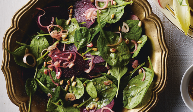 Spinach, Beetroot and Shallot Salad served in an olive coloured dish topped with toasted pine nuts