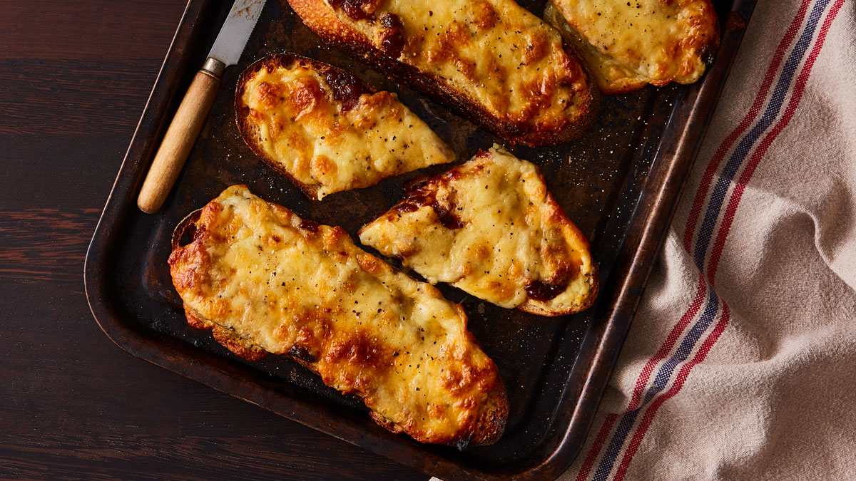 Booths Sourdough Rarebit served on a roasting tray with one portion sliced in half