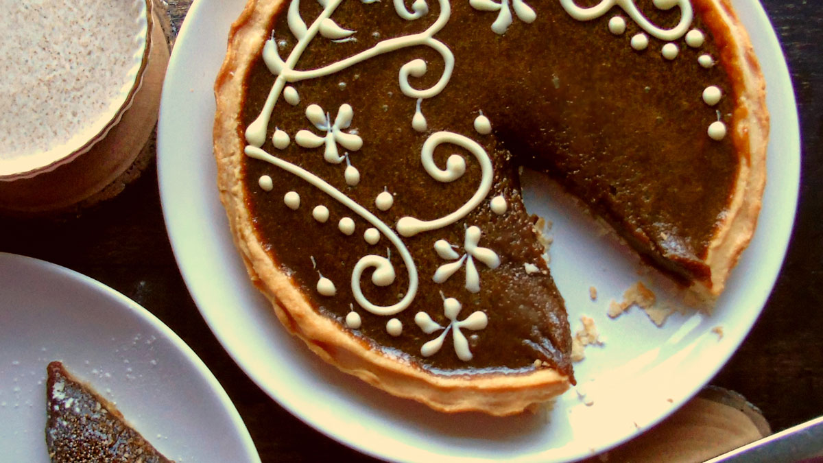 Butterscotch Tart with a Lancaster Honey and Cinnamon Cream served on a white plate with a slice removed