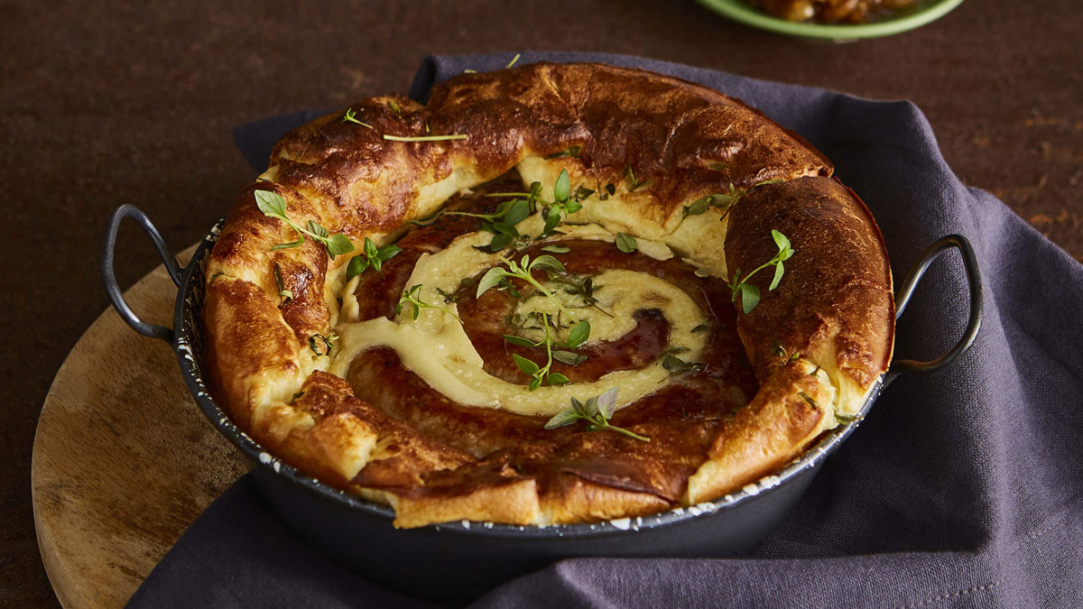 Catherine Wheel Sausage Toad-In-The-Hole served in a casserole dish topped with thyme