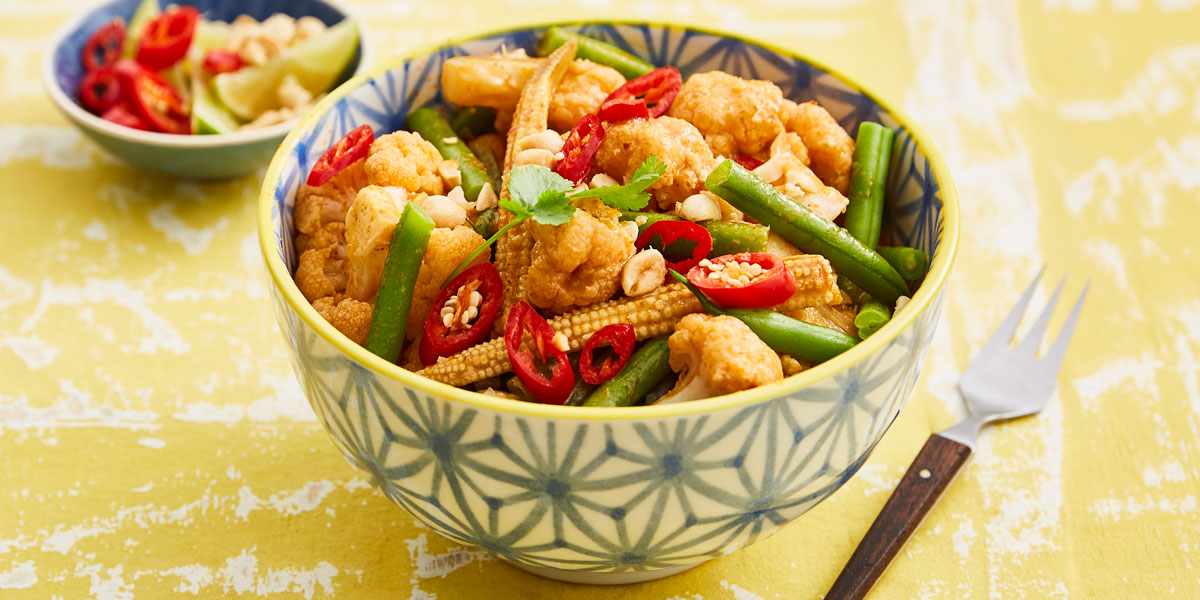 Quick Thai Red Cauliflower Curry served in a patterned bowl topped with fresh red chillies