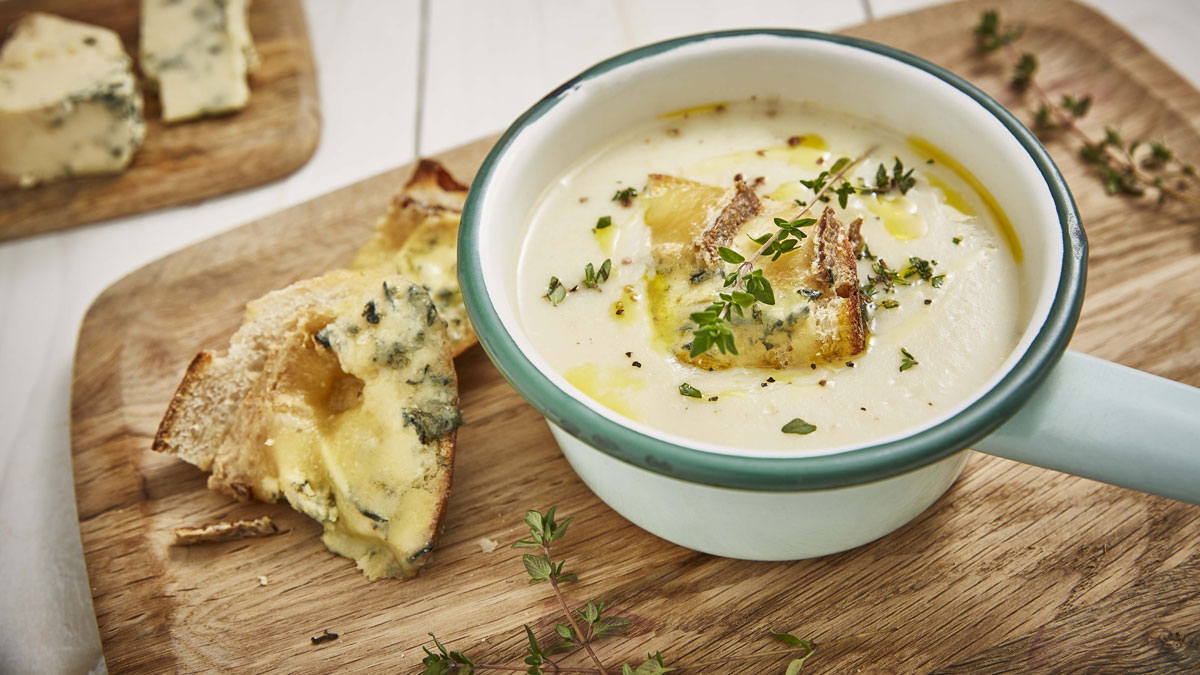 Cauliflower Soup with Blue Cheese Croutons served on a wooden board and topped with chives