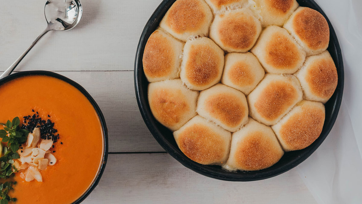 Northern Dough Co Cheesy Stuffed Doughballs served in a black tin, next to a bowl of soup to eat with