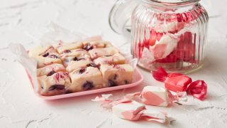 Cherry Ripple Fudge served on parchment paper next to a glass jar of wrapped portions