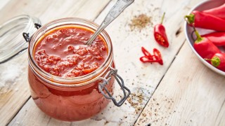 Lancashire Chilli Chutney served in a glass jar with sliced chillies in the background