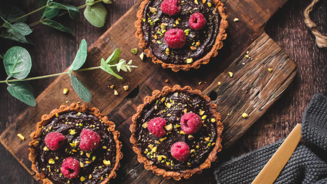 Chocolate and Honey Tarts topped with fresh raspberries and crushed pistachios