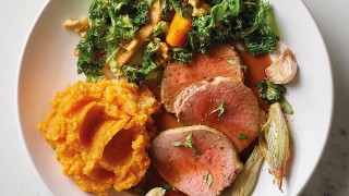 Roast Veal Tenderloin with Sweet Potato Mash, Roast Vegetables and Gravy served on a white plate