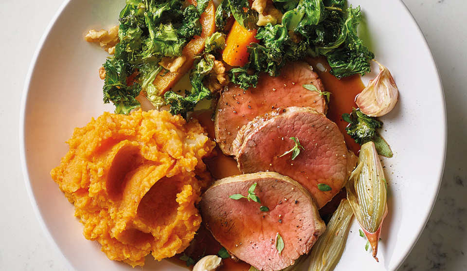 Roast Veal Tenderloin with Sweet Potato Mash, Roast Vegetables and Gravy served on a white plate