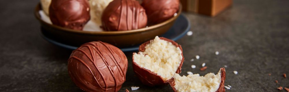 Coconut and Chocolate Truffles served in a gold bowl, with one truffle sliced to see the inside