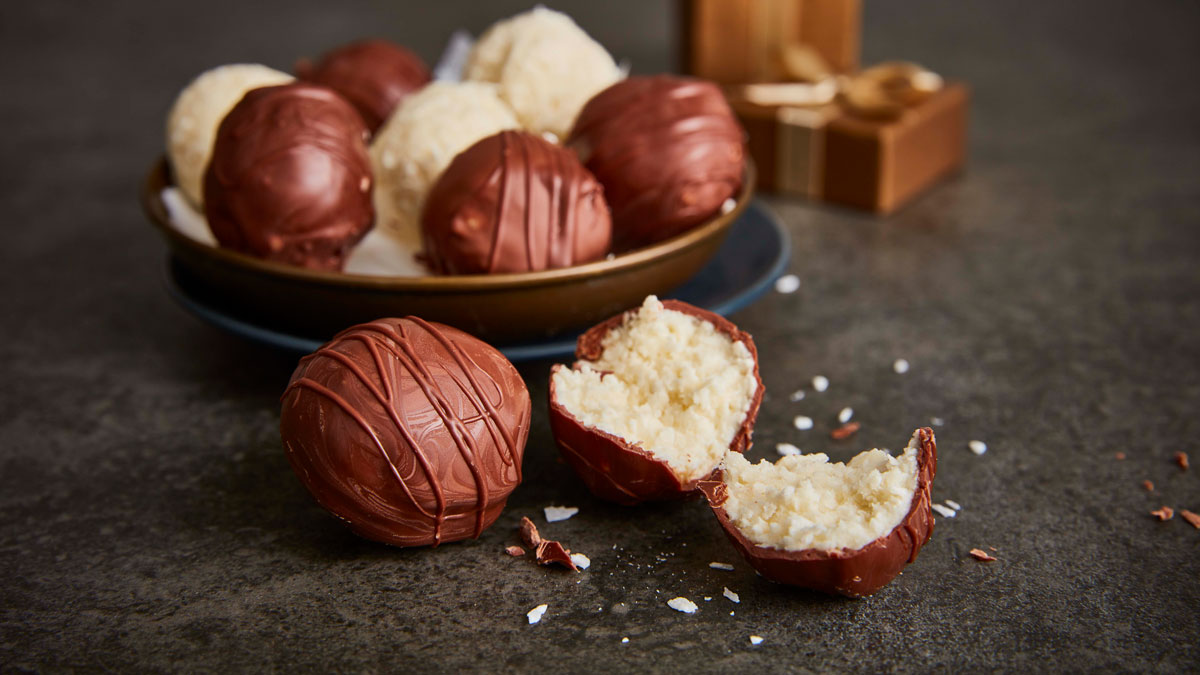 Coconut and Chocolate Truffles served in a gold bowl, with one truffle sliced to see the inside