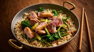 Sticky Orange and Ginger Stir Fry Duck served in a wok next to wooden chopsticks