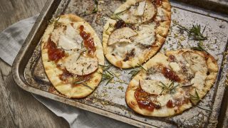 Goats' Cheese, Caramelised Onion and Pear Flatbreads topped with rosemary and served on a baking tray