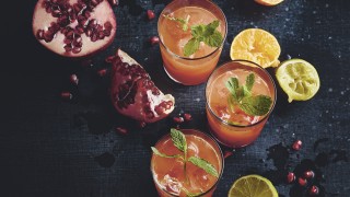 Engergy Booster Juice served in three glasses surrounded pomegranate and squeezed limes