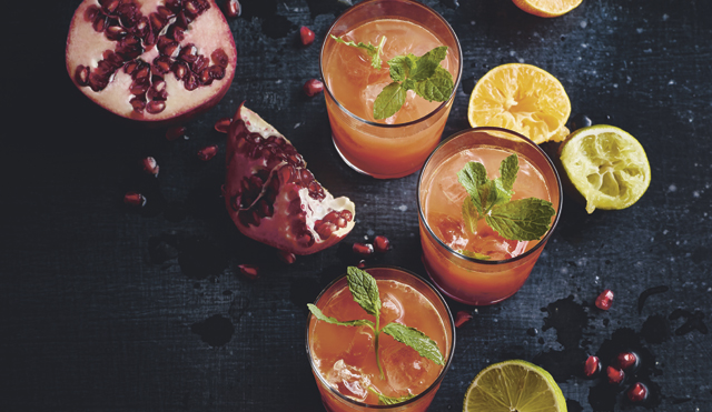 Engergy Booster Juice served in three glasses surrounded pomegranate and squeezed limes