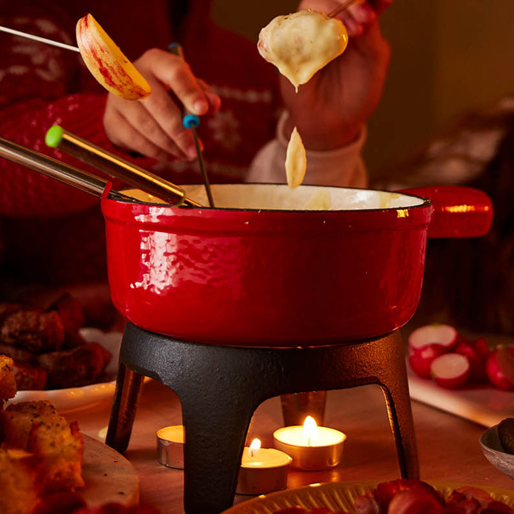 Image of people dipping various foods into a pot of cheese fondue