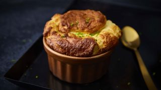 Booths Country Four Cheese Souffle served in a bronze ramekin on a baking tray topped with chives