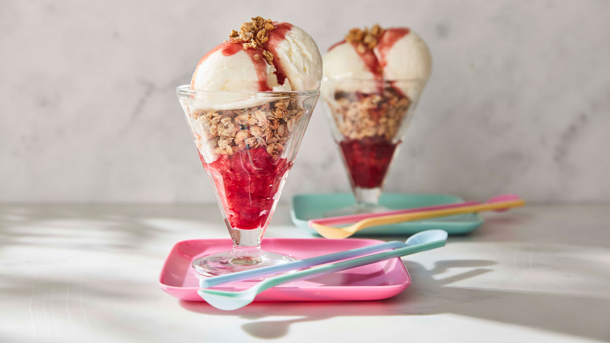 Frozen Yoghurt Breakfast Sundae served in glass dishes topped with raspberry coulis and granola