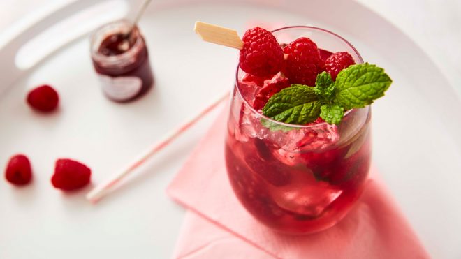 Gin and Jam Cocktail served in a glass with fresh raspberries and mint