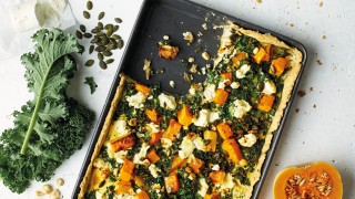 Squash, Kale and Goats Cheese Tart served in a baking grey with a portion removed