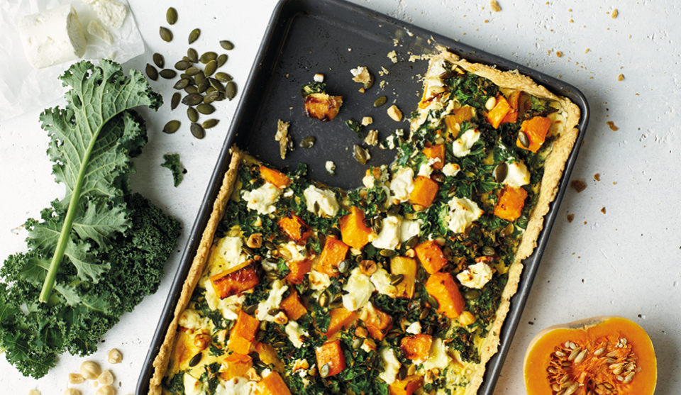 Squash, Kale and Goats Cheese Tart served in a baking grey with a portion removed