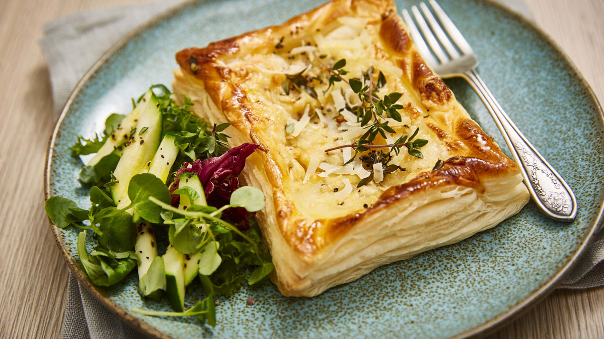 Goats' Cheese, Potato and Thyme Tart served on a blue plate with a side salad