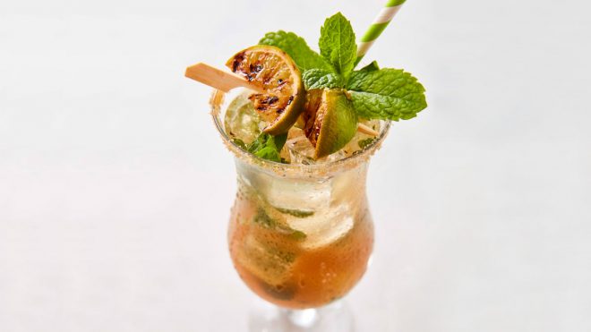 Grilled Mojito Mocktail served in a tall glass with grilled lime wedges and fresh mint